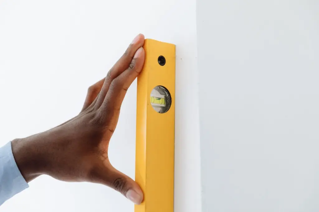 Mano apoyando un nivel de burbuja en vertical sobre una pared