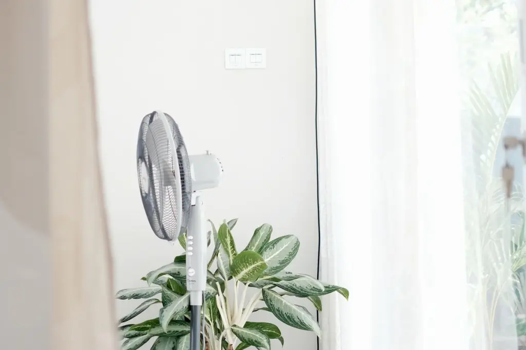 Ventilador de pie junto a una ventana luminosa en verano